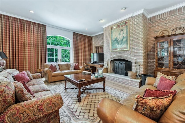 living room featuring a brick fireplace, light hardwood / wood-style flooring, brick wall, and ornamental molding