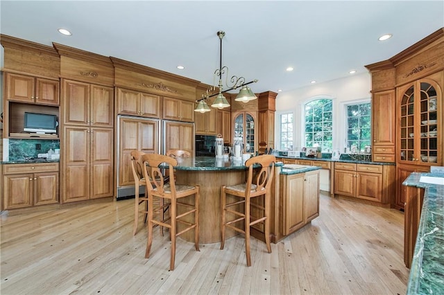 kitchen with a kitchen breakfast bar, light wood-type flooring, tasteful backsplash, pendant lighting, and a center island