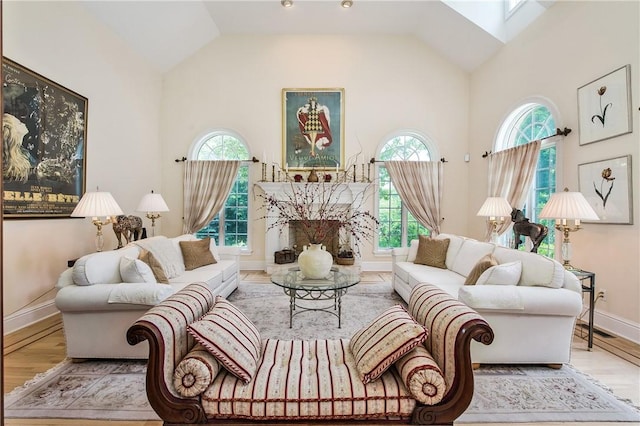 living room with a skylight, light hardwood / wood-style flooring, high vaulted ceiling, and a healthy amount of sunlight