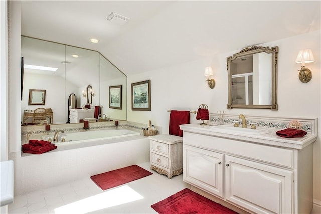 bathroom featuring tiled tub, vanity, and lofted ceiling