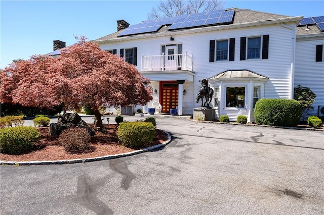 view of front of property featuring solar panels and a balcony