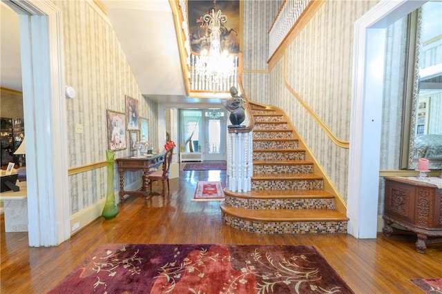 stairs with wood-type flooring and an inviting chandelier