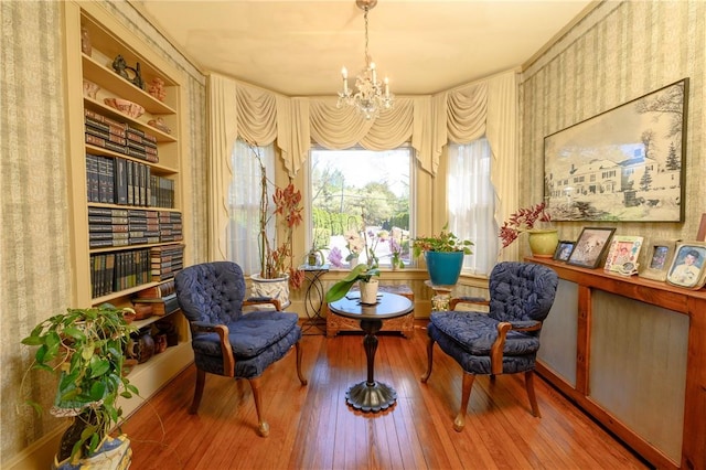 living area with a chandelier, hardwood / wood-style floors, and built in shelves