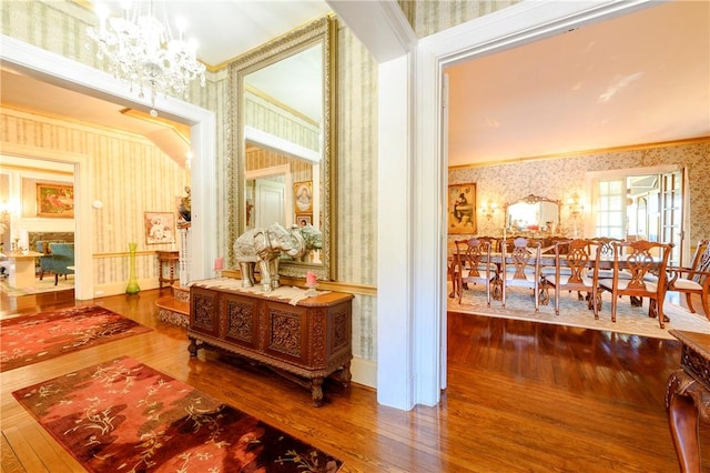 hall with hardwood / wood-style floors, crown molding, and a chandelier