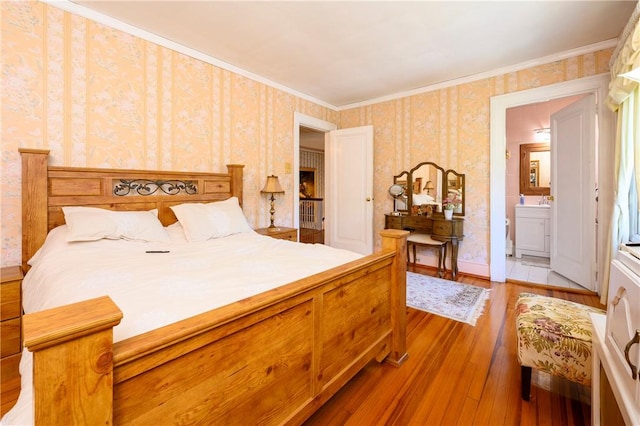 bedroom featuring wood-type flooring, crown molding, and ensuite bath