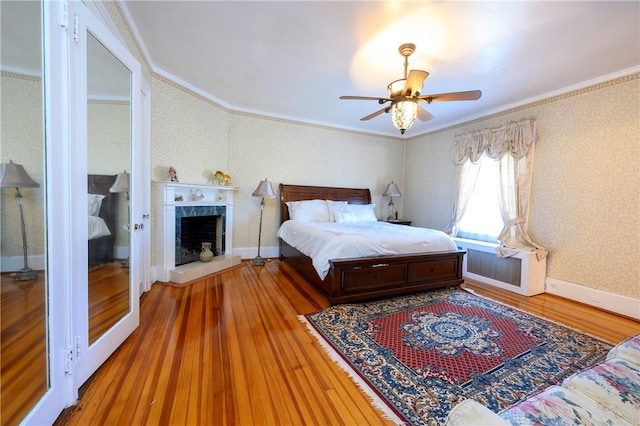 bedroom with hardwood / wood-style floors, radiator heating unit, ceiling fan, and ornamental molding