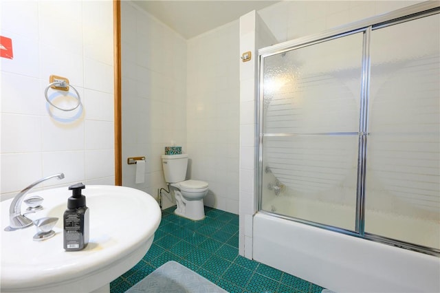 full bathroom with sink, shower / bath combination with glass door, tile walls, tile patterned flooring, and toilet