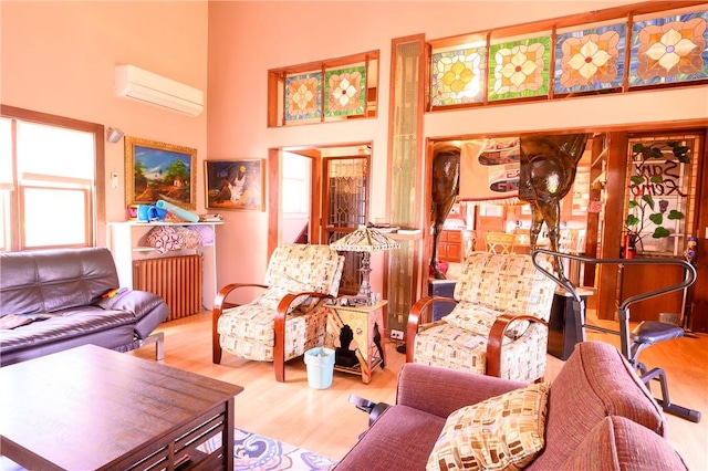 living room with radiator heating unit, light hardwood / wood-style floors, a wall unit AC, and a high ceiling