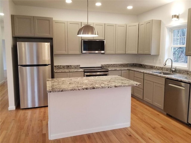 kitchen with appliances with stainless steel finishes, light wood-type flooring, pendant lighting, and sink