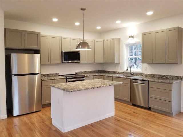 kitchen featuring pendant lighting, a center island, sink, light hardwood / wood-style flooring, and stainless steel appliances