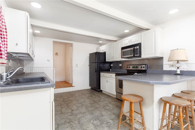 kitchen featuring appliances with stainless steel finishes, white cabinetry, a kitchen breakfast bar, and sink