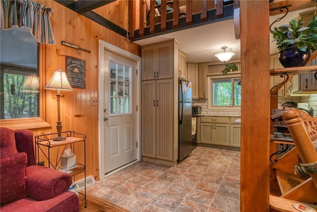 interior space featuring black refrigerator, wooden walls, and tasteful backsplash