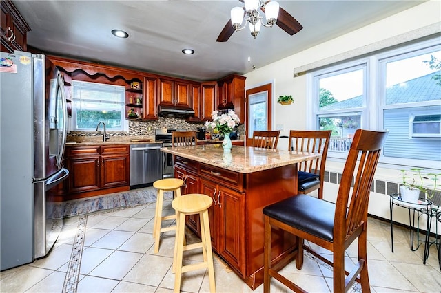 kitchen featuring light stone countertops, ceiling fan, decorative backsplash, light tile patterned floors, and appliances with stainless steel finishes