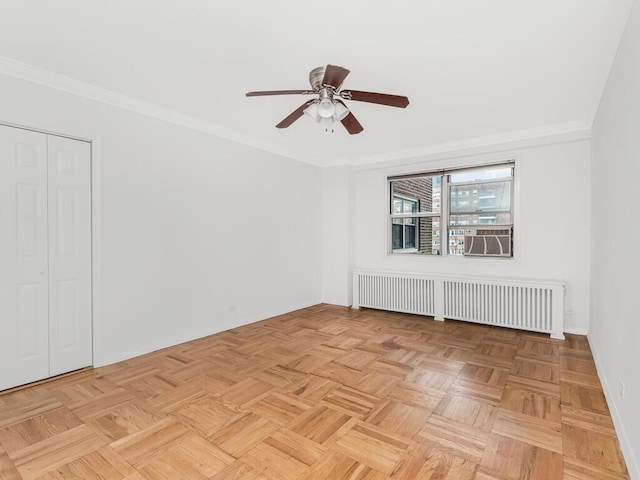 spare room with radiator, crown molding, and light parquet flooring