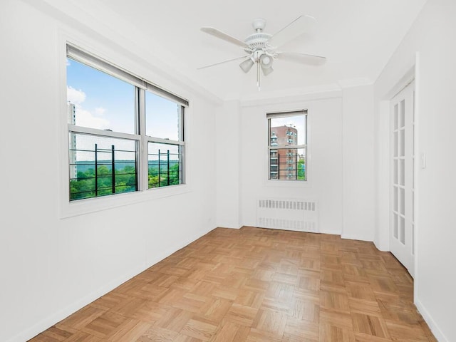 spare room featuring light parquet flooring, plenty of natural light, radiator, and ceiling fan