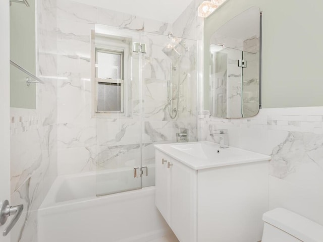 full bathroom featuring vanity, combined bath / shower with glass door, tile walls, and toilet