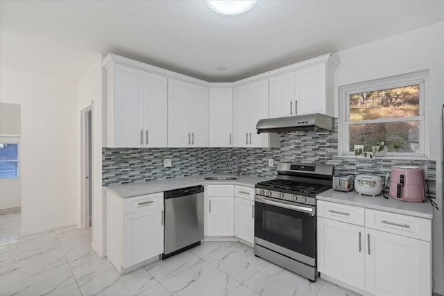 kitchen with backsplash, stainless steel appliances, white cabinetry, and sink