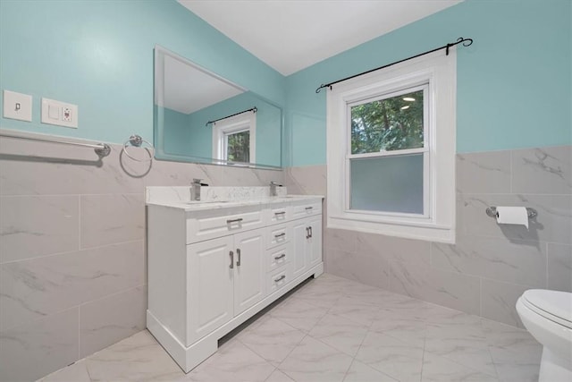 bathroom featuring vanity, toilet, a wealth of natural light, and tile walls