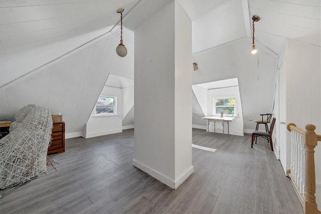 additional living space with beam ceiling, hardwood / wood-style flooring, a wealth of natural light, and wooden walls