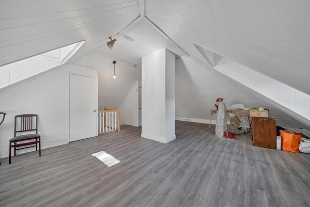 bonus room with vaulted ceiling with skylight and wood-type flooring