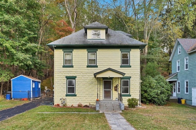 view of front of home with a storage unit and a front lawn