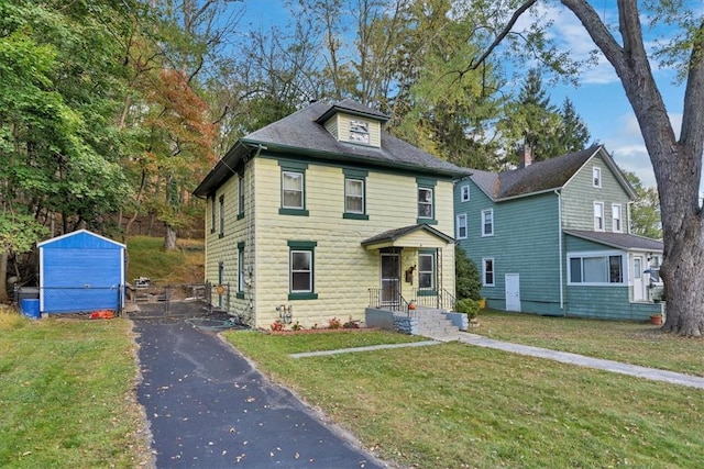 view of front of property with a storage unit and a front yard