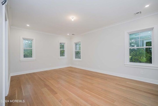 spare room featuring plenty of natural light, ornamental molding, and light wood-type flooring