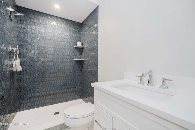 bathroom featuring vanity, toilet, and a tile shower