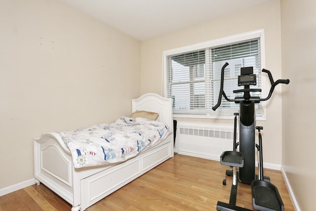 bedroom featuring radiator heating unit and light wood-type flooring