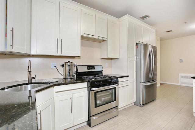 kitchen featuring sink, white cabinets, dark stone counters, and appliances with stainless steel finishes