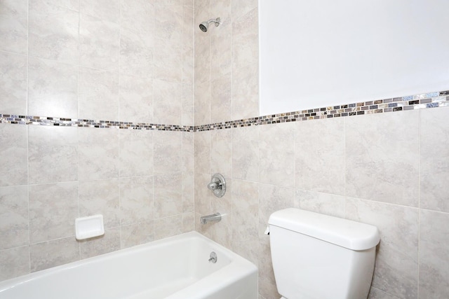 bathroom with tiled shower / bath combo, tile walls, and toilet