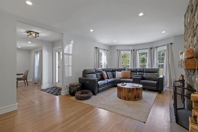 living room featuring a stone fireplace and light hardwood / wood-style flooring