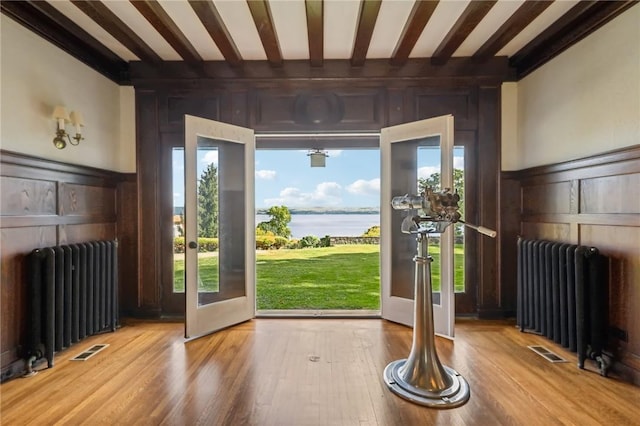 doorway with hardwood / wood-style flooring, a water view, and radiator heating unit