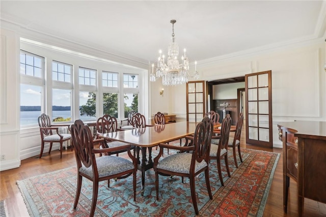 dining room featuring wood-type flooring, a water view, french doors, and a healthy amount of sunlight