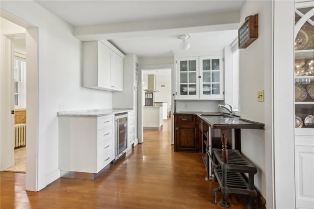 kitchen with radiator, hardwood / wood-style floors, white cabinets, and beverage cooler