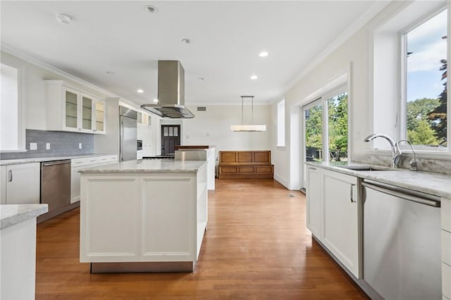 kitchen featuring stainless steel appliances, a center island, white cabinetry, hanging light fixtures, and range hood