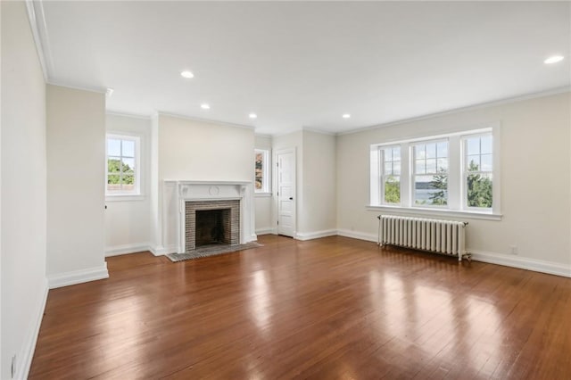 unfurnished living room with dark hardwood / wood-style floors, radiator heating unit, ornamental molding, and a brick fireplace