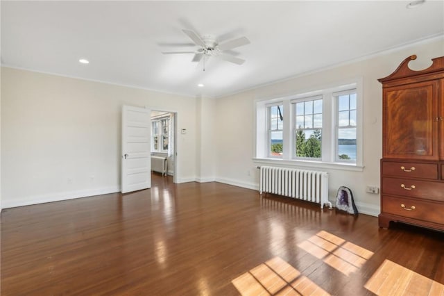 spare room featuring radiator heating unit, dark hardwood / wood-style floors, ceiling fan, and crown molding