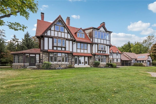 rear view of house featuring a lawn and a sunroom