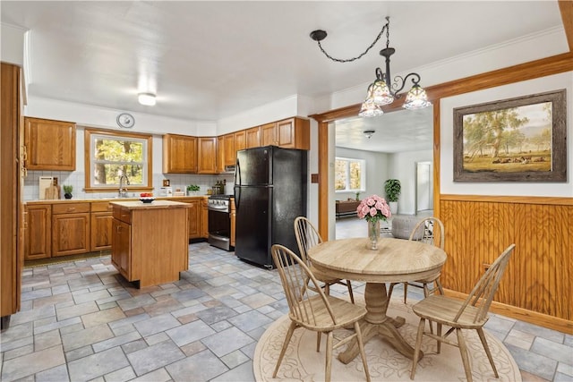 kitchen featuring light countertops, stainless steel range with gas stovetop, a center island, backsplash, and freestanding refrigerator