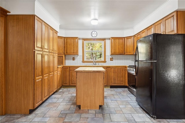 kitchen featuring stainless steel gas range oven, tasteful backsplash, a kitchen island, a sink, and freestanding refrigerator