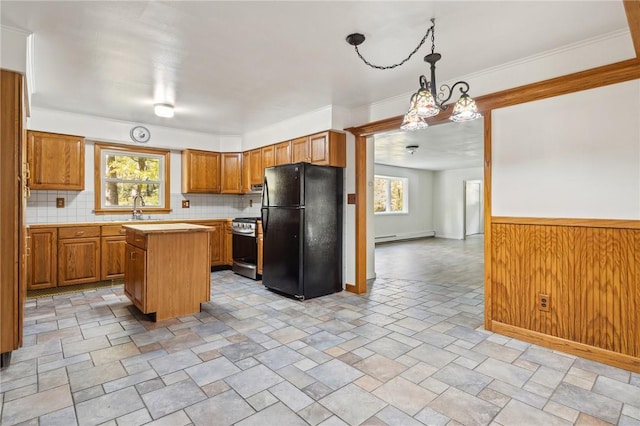 kitchen with light countertops, a kitchen island, a sink, gas range, and freestanding refrigerator