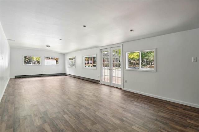 unfurnished living room with plenty of natural light, baseboards, wood finished floors, and french doors
