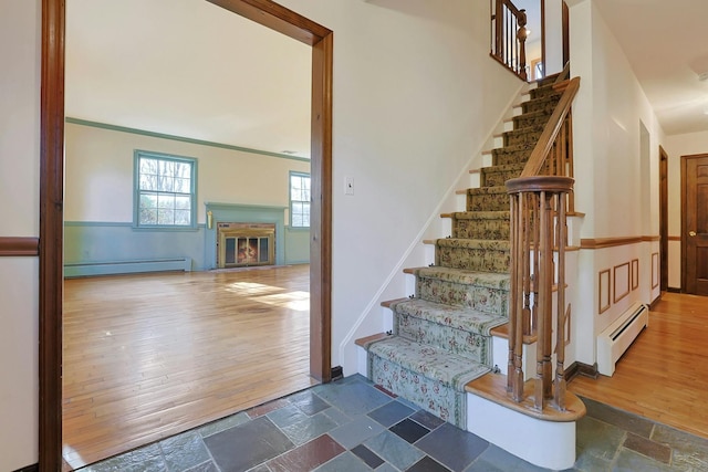 stairs with wood-type flooring, a high ceiling, and a baseboard heating unit