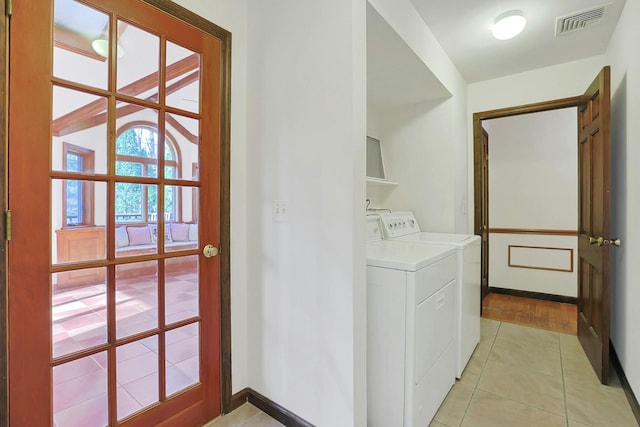 clothes washing area with washing machine and clothes dryer and light hardwood / wood-style flooring