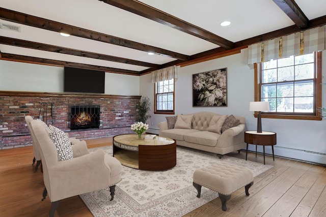 living room featuring beamed ceiling, light hardwood / wood-style floors, a baseboard radiator, and a brick fireplace