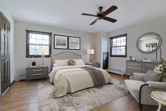 bedroom featuring light hardwood / wood-style flooring, ceiling fan, and a baseboard heating unit