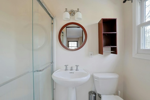 bathroom featuring toilet and a shower with shower door