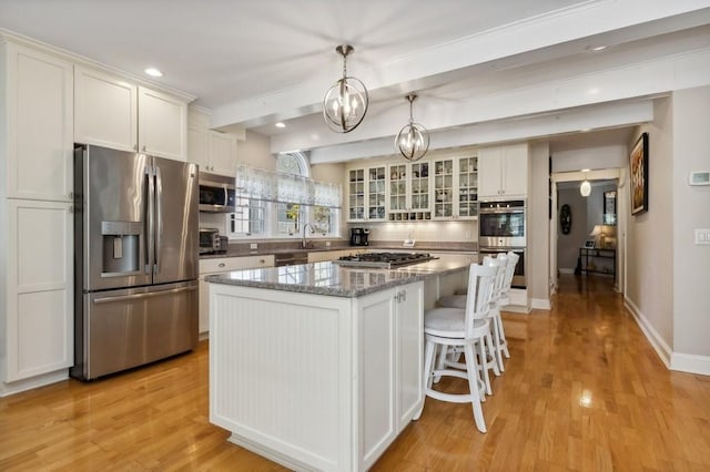 kitchen featuring light wood-type flooring, a center island, stainless steel appliances, and white cabinetry