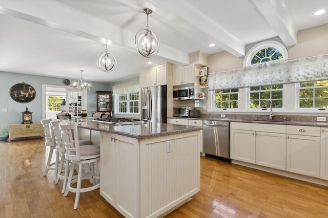 kitchen featuring sink, hanging light fixtures, light hardwood / wood-style floors, a kitchen island, and stainless steel appliances